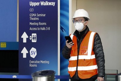 Un trabajador, con mascarilla, sale del recinto ferial de Gran Via, donde se iba a celebrar el Mobile. 