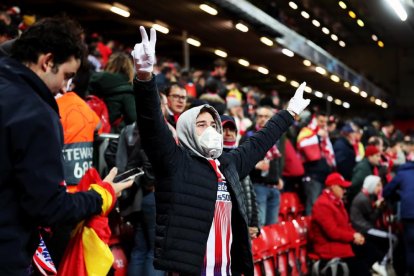 Un aficionado del Atlético, con mascarilla y guantes, celebra la clasificación del Atlético en Anfield.