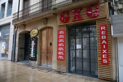 Tiendas cerradas en el Eix Comercial con anuncios de rebajas.