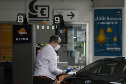 Un conductor con mascarilla, repostando en una estación de servicio.