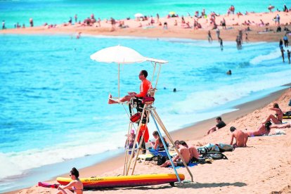 Diverses persones gaudint ahir del sol en una platja de Barcelona.