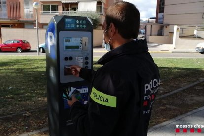 Un agente de los Mossos, en un parquímetro. 