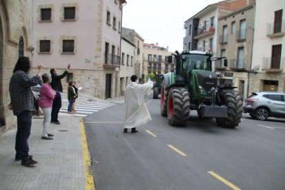 El mosén de Bellpuig bendiciendo uno de los tractores participantes en el desfile de los Tres Tombs.