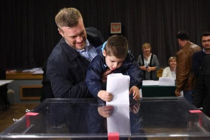 Un niño deposita el voto de su progenitor en una urna, ayer.