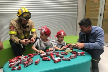 Dos bomberos juegan con dos niños del hospital Sant Joan de Déu durante la sesión de fotos. 