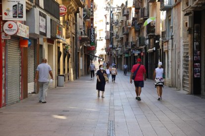 El carrer del Carme, amb la majoria de les botigues tancades i alguns passejants, ahir.