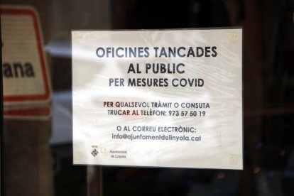 Un cartell informatiu sobre la suspensió de l'atenció al públic pel brot de covid-19 a la porta de l'Ajuntament de Linyola.