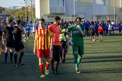 Jugadors del Lleida es dirigeixen, abatuts, fins als vestidors, mentre que al fons la plantilla i l’afició local celebren que són campions de grup.