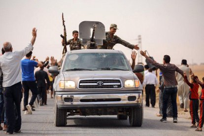 Civiles sirios saludan a tropas de Al Asad en la ciudad de Tel Tamer, en el noreste del país.