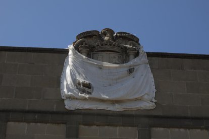 Medio tapado  -  El escudo con el águila franquista esculpido en piedra en lo alto del edificio lleva años medio tapado con una lona blanca, que periódicamente se descuelga y lo deja de nuevo al descubierto, todo o en parte. Actualmente, present ...