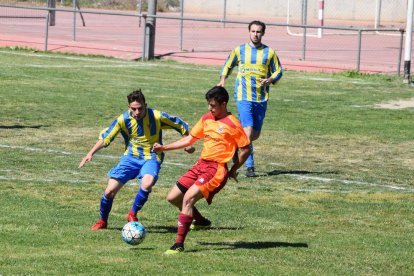 Un jugador del Rosselló disputa el balón ante la presencia de dos rivales.