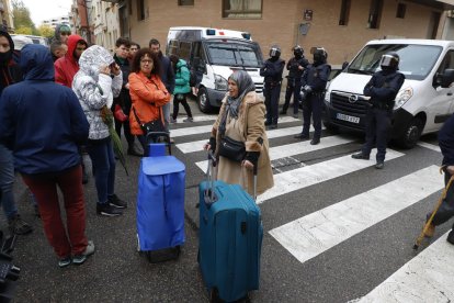 Algunos de los afectados saliendo del bloque con sus enseres personales ante efectivos de los Mossos.