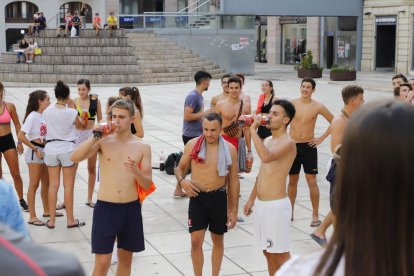 Alumnes bevent i fent flexions com a part de les novatades, ahir a la plaça Sant Joan.