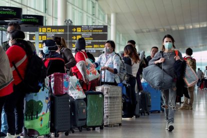 Diversos viatgers a l’aeroport de Barcelona, molts d’ells amb màscares.