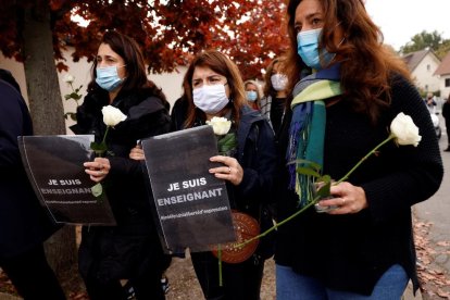 Diverses companyes del professor assassinat porten flors per honrar la víctima.