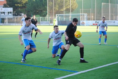 Dos jugadors del Mollerussa pressionen un visitant, que intenta controlar la pilota.