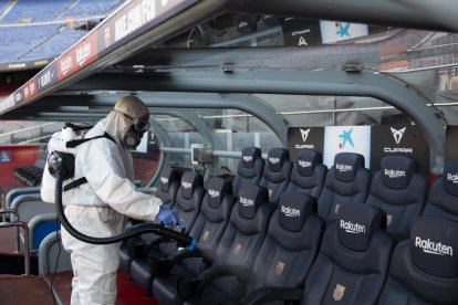 Un operari desinfecta les banquetes del Camp Nou abans del partit contra el Leganés.