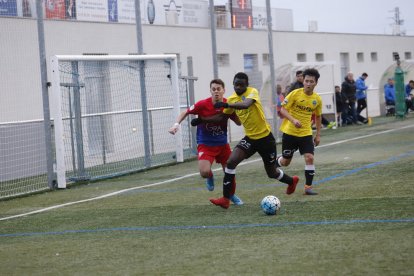 Un jugador del Lleida protegeix la bimba davant un jugador del Torrefarrera.