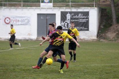 Un jugador visitant intenta controlar la pilota davant de la pressió dels rivals.