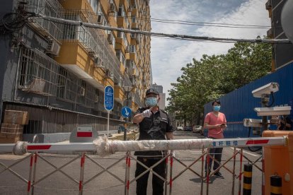 Un guàrdia de seguretat impedeix el pas a un carrer proper al mercat de Pequín infectat per Covid-19.