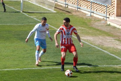 Un jugador del Montsó protegeix l’esfèric davant la pressió defensiva d’un jugador local.