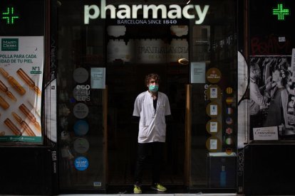 Un farmacèutic, ahir a les portes del seu establiment a Barcelona amb màscara.