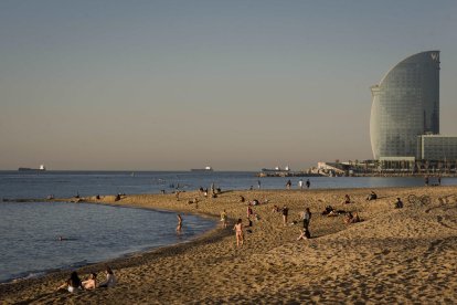 Desenes de persones a primera hora en una platja de Barcelona. Alguns prenen el sol tot i les normes.