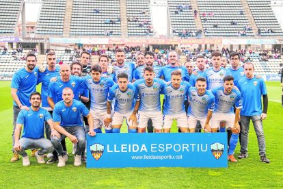 Los jugadores de un once titular del Lleida posan con aficionados antes de un partido.