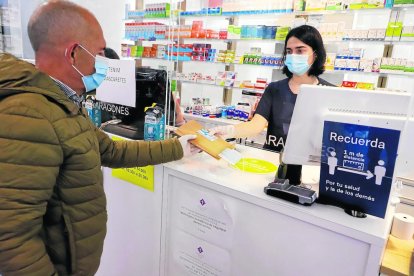 Un cliente recogiendo una mascarilla gratis con su tarjeta sanitaria en Lleida.