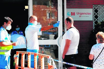 Un paramédico toma la temperatura a la salida de un centro sanitario de San Sebastián de los Reyes.