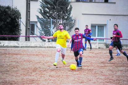 Un jugador del Castelldans intenta controlar la pilota davant d’un defensor del Bell-lloc.