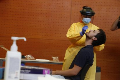 Imagen de un sanitario haciendo la PCR a un joven en el centro cívico de Balàfia.