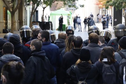 En primer plano, los manifestantes y los antidisturbios. Al fondo, el estand de Vox en la calle Major. 