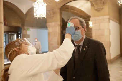 Una treballadora del Parlament pren la temperatura al president, Quim Torra.