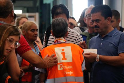 Diversos usuaris demanen informació a un empleat de Renfe.