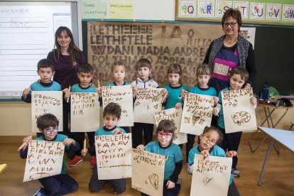 Los escolares muestran letras mayúsculas que escribieron con cañas y tinta.