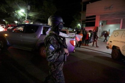 Agente armado junto a una camioneta que transporta un cadáver.