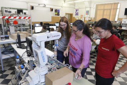 Las tres estudiantes, en una aula de prácticas con sus compañeros detrás.