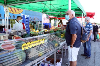 Clients amb mascaretes en una parada de fruita al mercadillo de Bonavista de Reus.