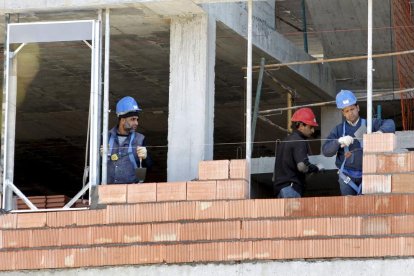 Tres trabajadores de la construcción, en la obra de un edificio de viviendas.