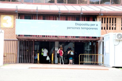 Personas ayer en la entrada del pabellón habilitado como albergue para la campaña de la fruta.