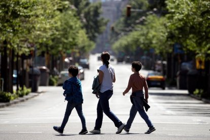 Tres personas cruzan una de las principales arterias de Barcelona, sin prácticamente tráfico, ayer.