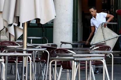 Un treballador de l’hostaleria prepara la terrassa d’un bar.