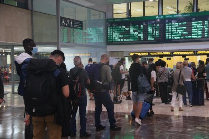 Diversos passatgers de Rodalies fent cua davant els mostradors d'informació a l'estació de Sants de Barcelona.