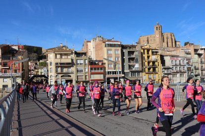 Un grupo de participantes de la Cursa de la Dona cruzando el río Segre en su paso por Balaguer.