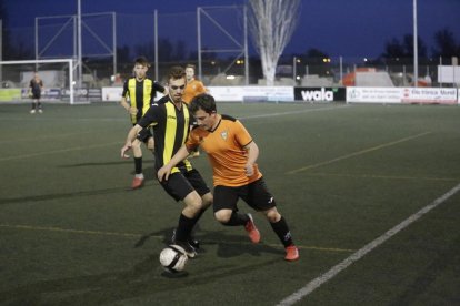 Un jugador de l’equip local i un altre del visitant es disputen la pilota.