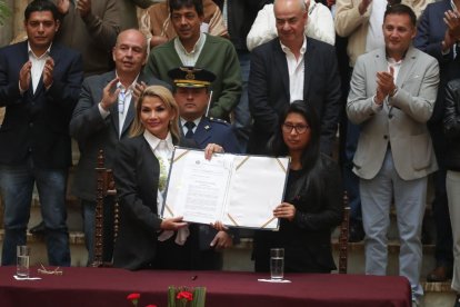 Áñez (izqda.) con el documento que convoca nuevas elecciones. 