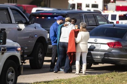 Familiares y amigos de una víctimas se abrazan junto a la iglesia.