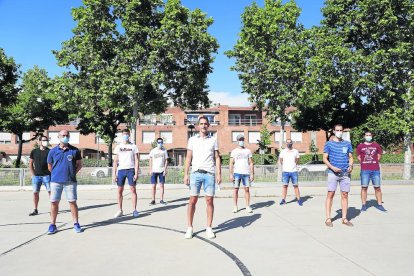 Lluís Tomàs posa con la mayoría de sus compañeros y cuerpo técnico, todos guardando la distancia de seguridad y con mascarilla. A la derecha, junto a su esposa e hijos.