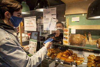 Un bar de Lleida, con carteles que indican la obligación del certificado, comprobando el de un cliente.